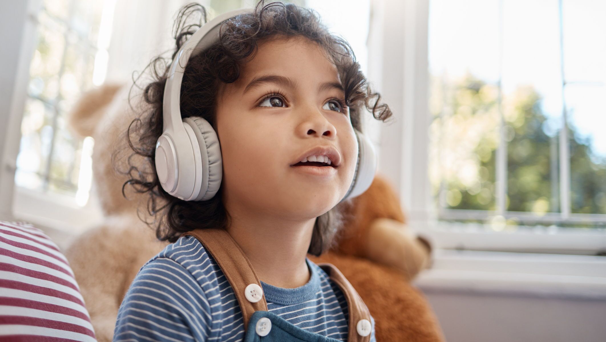 Young child listening to music or audiobooks through wireless headphones