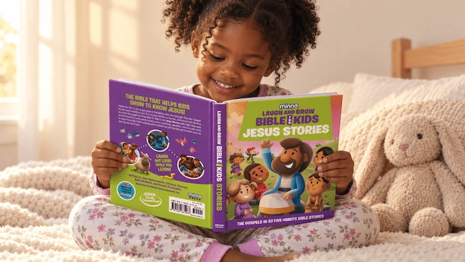 Smiling young girl sits on a cozy bed reading a colorful children's Bible stories book, with a plush bunny beside her.